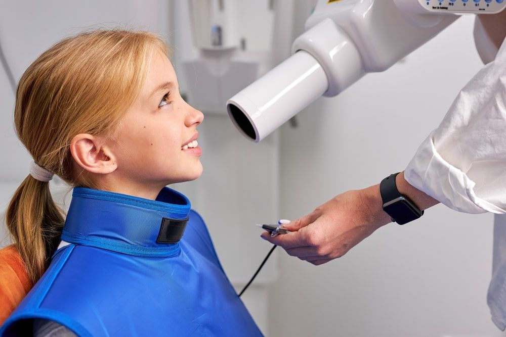 Girl sitting on dental couch while taking x-ray picture process